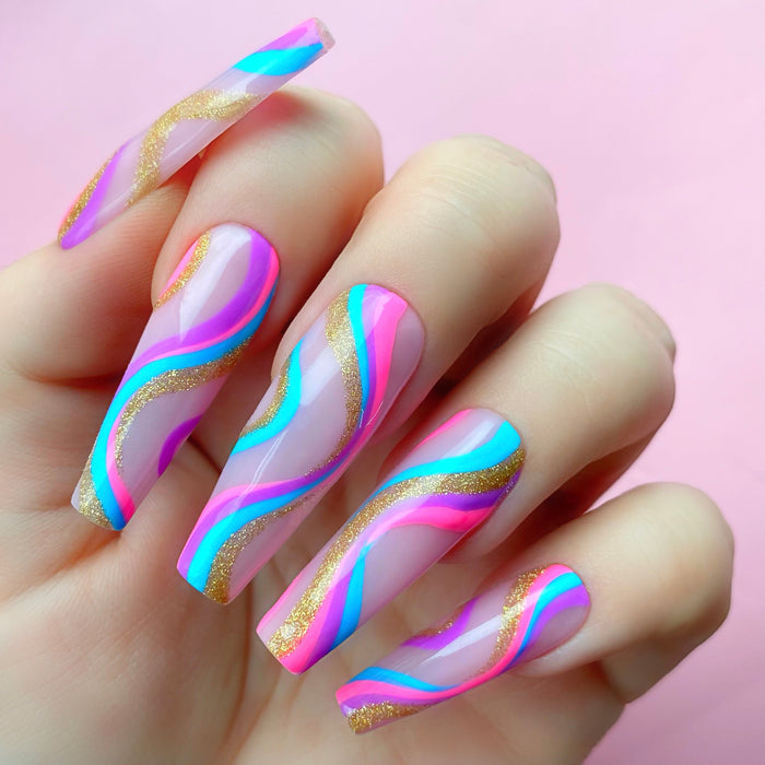 Gold Exhibit gel art bottle applied to nail extension as part of a swirly design