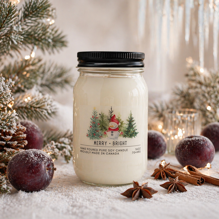 Jar of candle with Christmas-themed label surrounded by decorative elements on a snowy surface