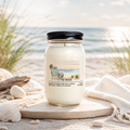 Candle in a jar labeled 'The Beach' on a sandy beach with ocean view