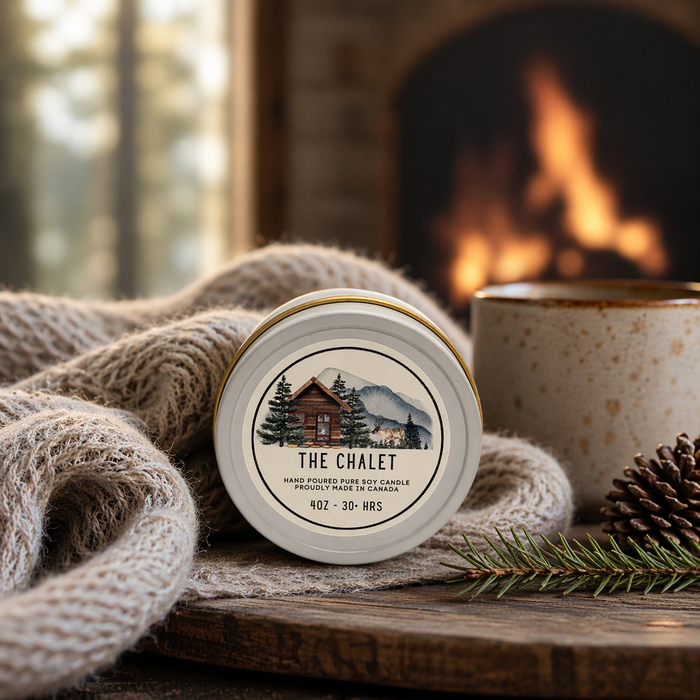 Candle labeled 'The Chalet' with a cozy fireplace and sweater in the background